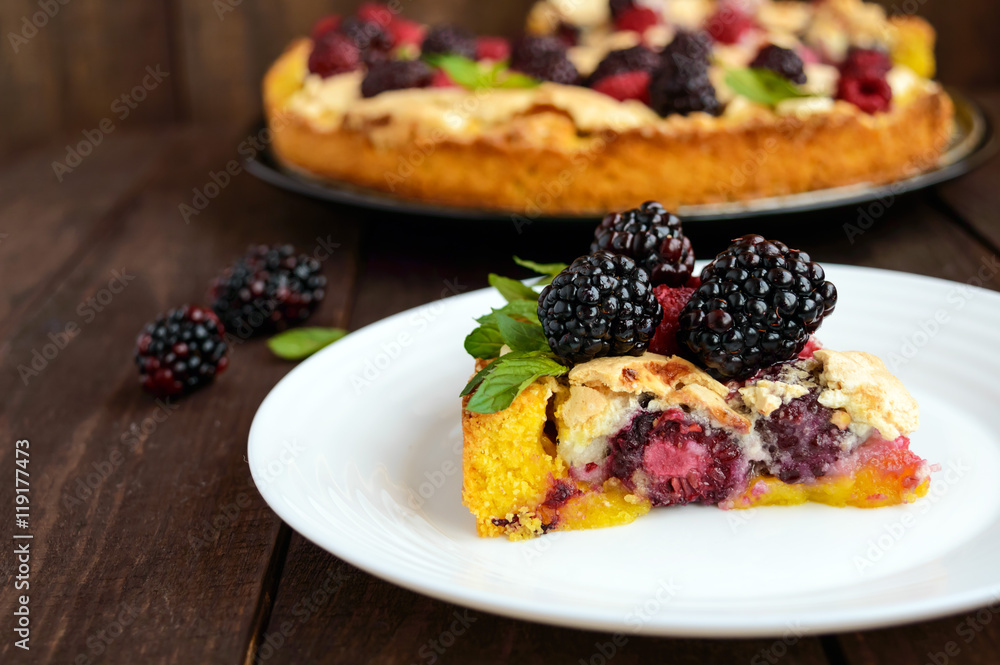 A piece of the pie (Tart) with fresh blackberries and raspberries, air meringue, mint decoration on a white plate A piece of the pie (Tart) with fresh blackberries and raspberries, air meringue, mint decoration on a white plate