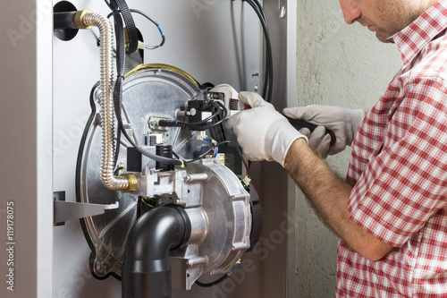 Fotografia plumber repairing a condensing boiler in the boiler room