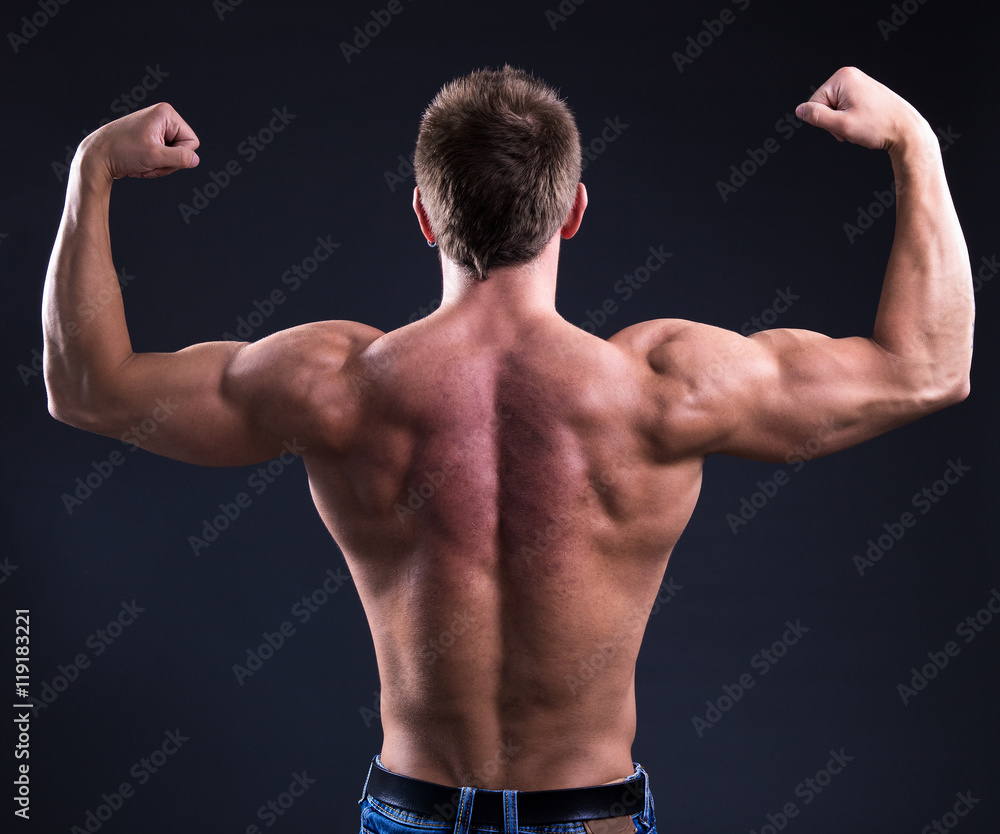 back view of muscular man showing his muscles over black backgro back view of muscular man showing his muscles over black backgro