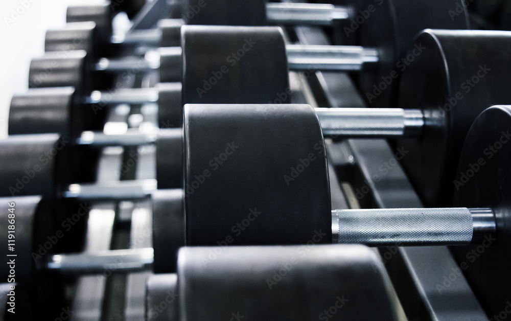 Obraz premium Hantle na siłowni do zajęć kulturystycznych dla mężczyzn, fitness oraz podejścia do ciężaru żelaznego.