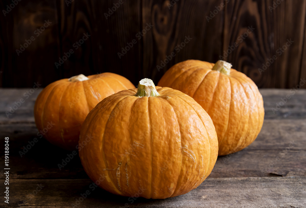 Three raw pumpkins on wooden background Three raw pumpkins on wooden background