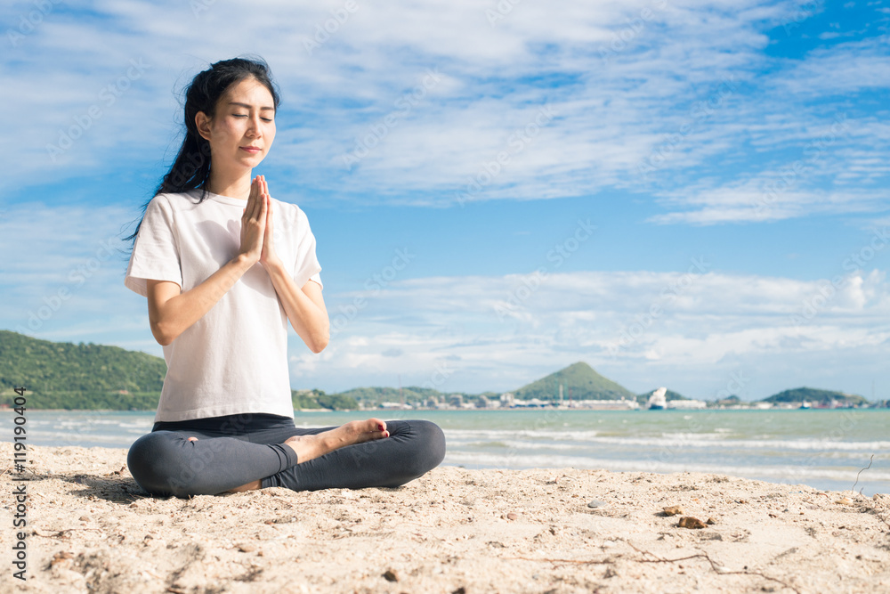 Fototapeta premium young woman practicing yoga on the beach