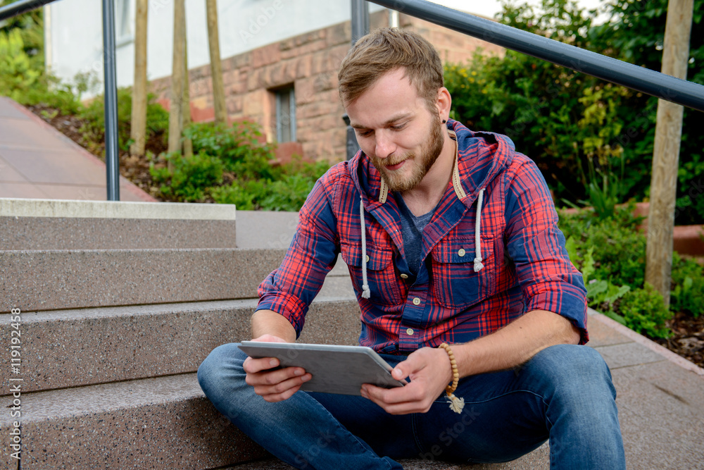 young man sitting on stairs and using tablet PC
