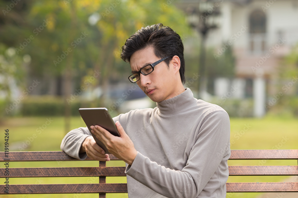 Obraz premium Man use tablet and thinking at park