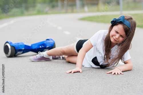 The girl fell from the hoverboard in the park photo