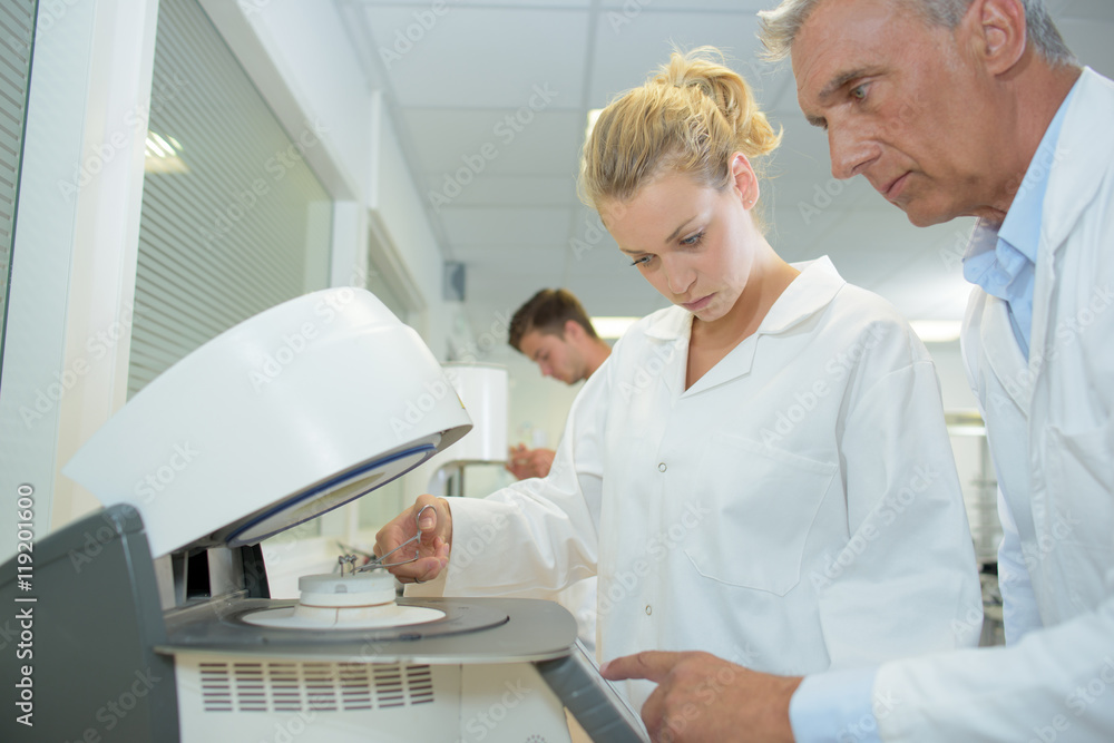 Obraz premium Male and female technicians using machine in laboratory