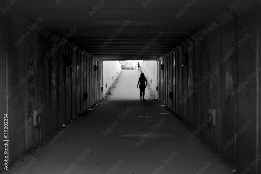 Girl walking on a grey urban pedestrian tunnel