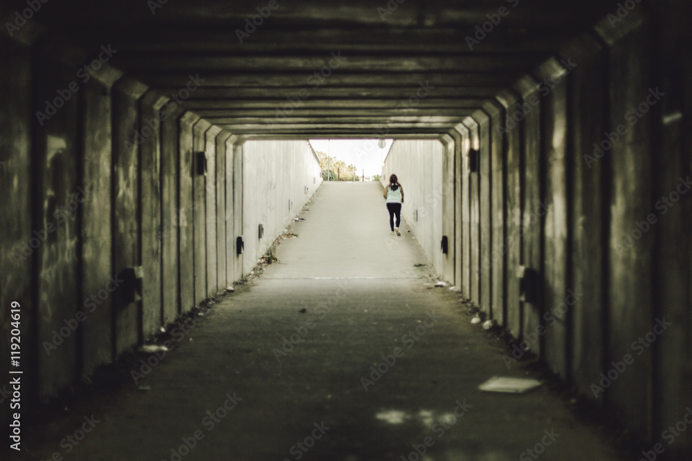 Girl walking on a dark tunnel path Girl walking on a dark tunnel path