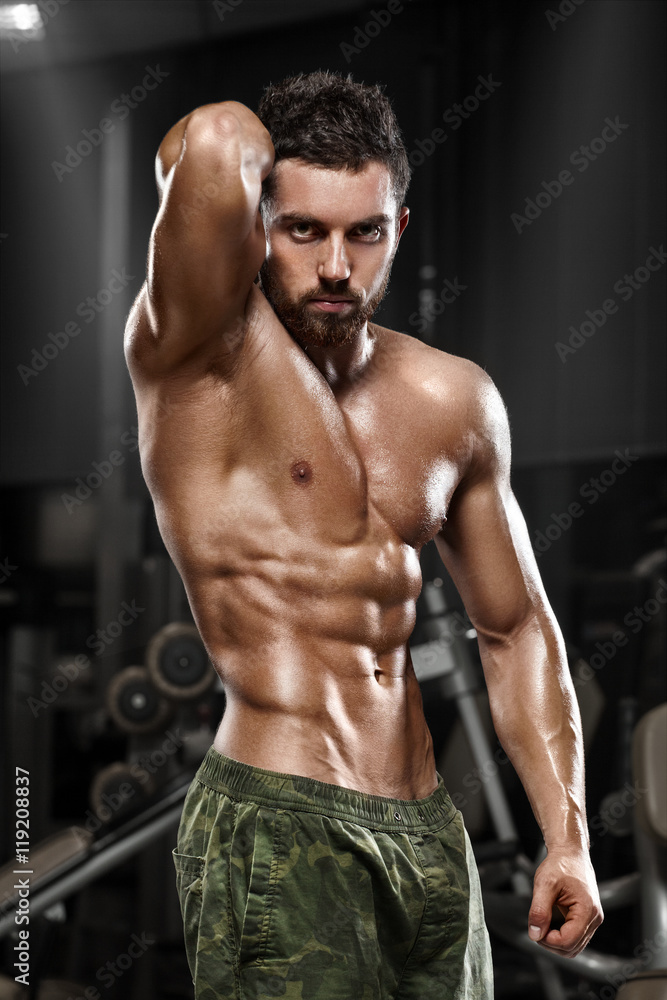 Sexy muscular man posing in gym, shaped abdominal. Strong male naked torso abs, working out