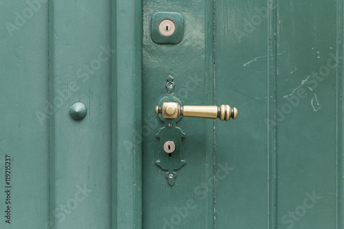 Eine grün bemalte Holztür mit goldfarbenem Griff, Metallnieten und zwei Schlössern. © Andreas