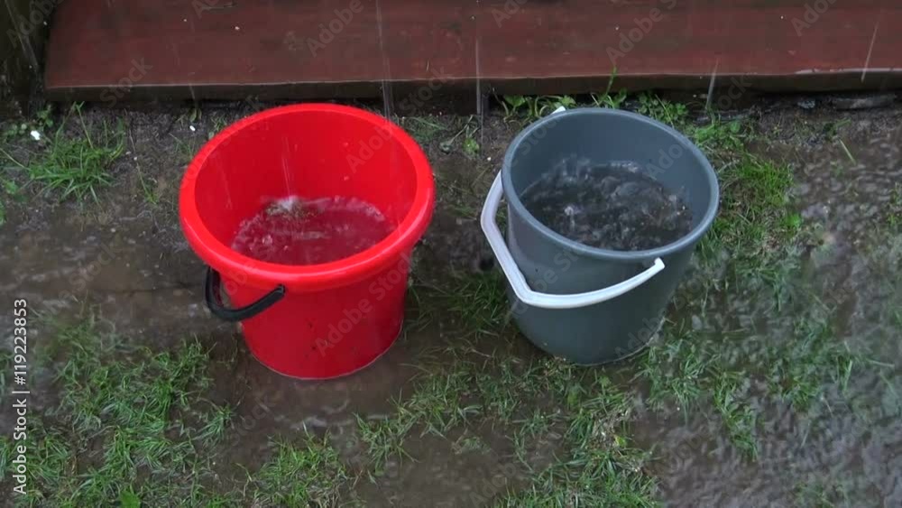 Water running into plastic buckets from roof during summer rain Water running into plastic buckets from roof during summer rain