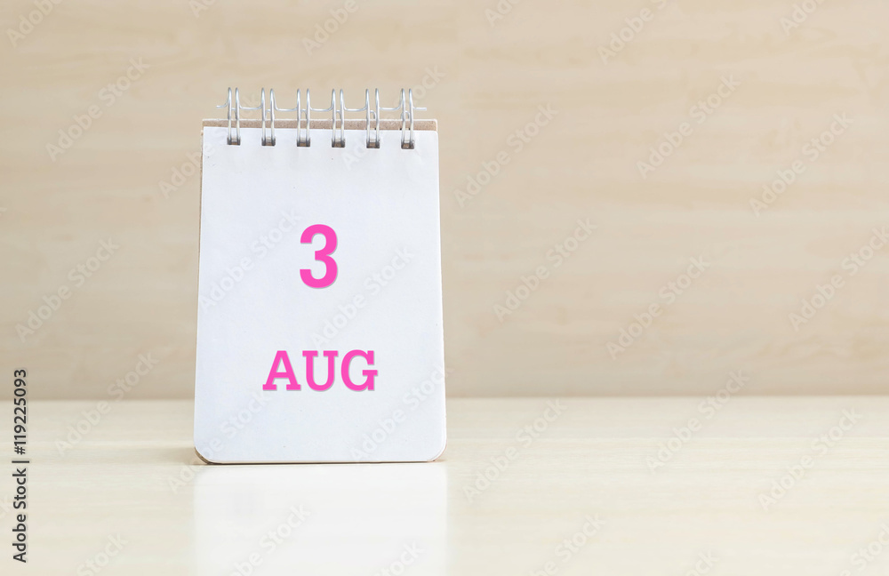 Closeup surface note book with pink 3 aug word in page on blurred brown wood desk and wood wall textured background with copy space under window light Closeup surface note book with pink 3 aug word in page on blurred brown wood desk and wood wall textured background with copy space under window light