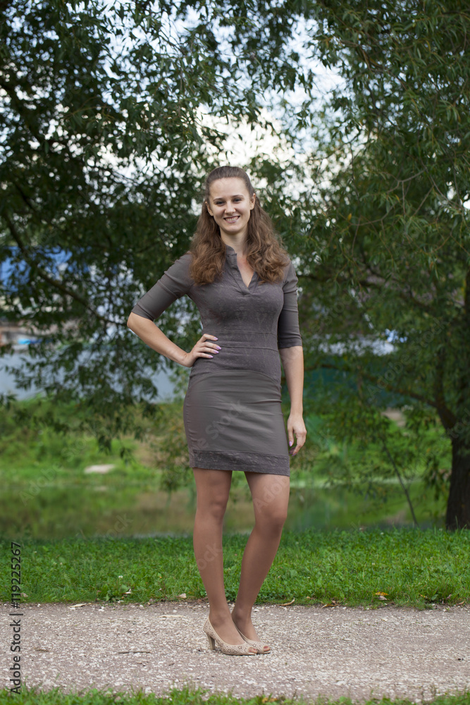 Young beautiful woman in brown dress in the summer park