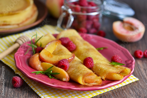 Vanilla pancakes with caramelized peaches, raspberries and honey