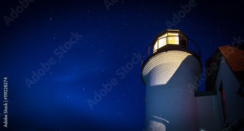 Lighthouse Beacon On A Starry Night. The Point Betsie Lighthouse beacon against a starry sky background. In panoramic orientation with copy space.