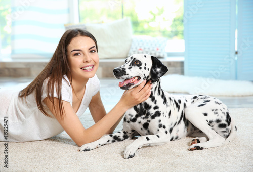 Owner with her dalmatian dog lying on a carpet