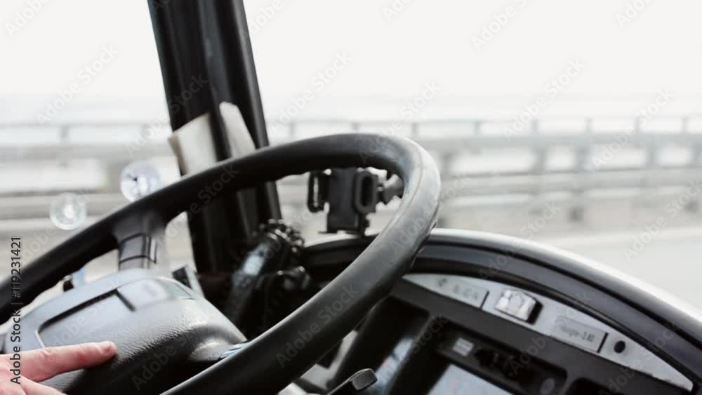 Hand of driver on black steering wheel of bus moving on motorway focus in. Day Hand of driver on black steering wheel of bus moving on motorway focus in. Day