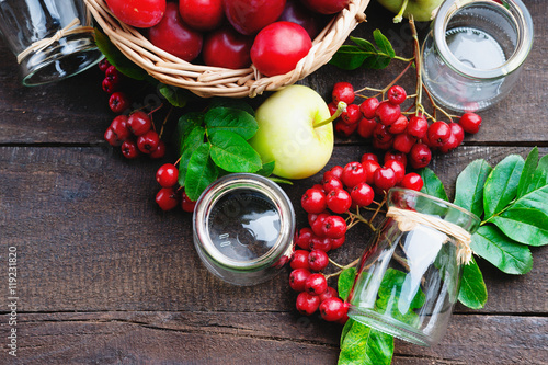 Plums in a basket, apples, rowanberry and glass jars photo