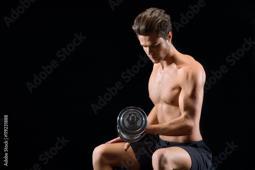 Handsome male athlete training with dumbbell
