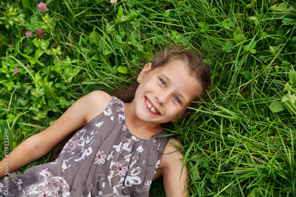 Happy little girl is lying on grass Happy little girl is lying on grass