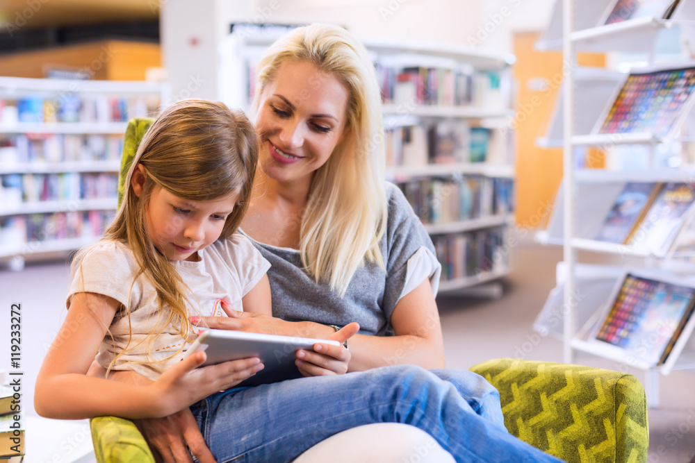 Mother with daughter look at their touchpad tablet device togeth Mother with daughter look at their touchpad tablet device togeth