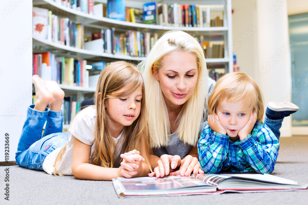 Fototapeta premium Mother with little girl and boy read book together