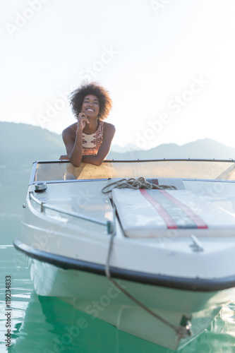 A stunningly beautiful afro woman driving a speedboat and having © Myvisuals