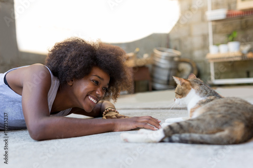 Beautiful afro american woman with her cat on the terrace. Conce