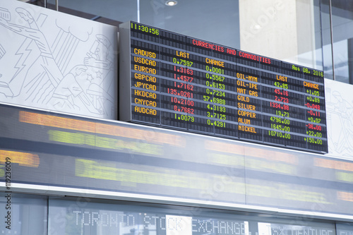 Fotografie The currency exchange rates displayed at the Toronto Stock Exchange with stock ticker in blurred motion underneath