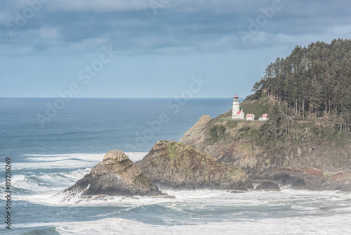 Coastal view of Heceta head lightstation in Yachats, Oregon with crashing waves and fog during storm clouds