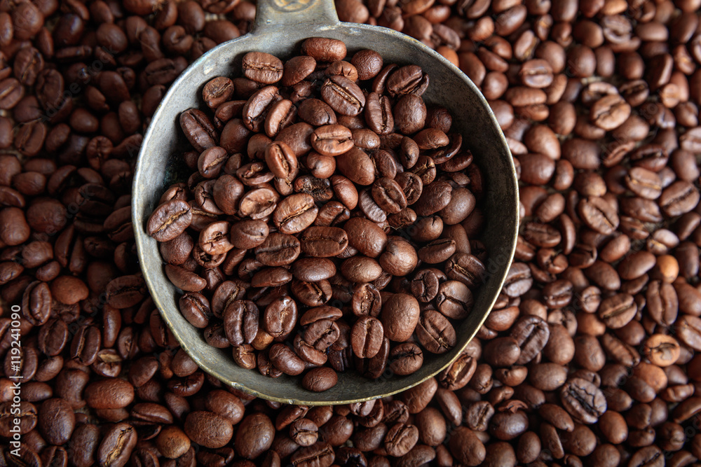 Coffee beans background and a metal spoon