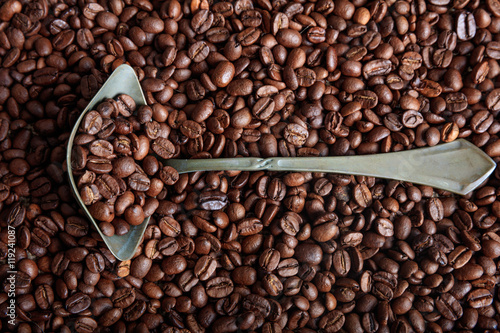 Coffee beans background and a metal spoon