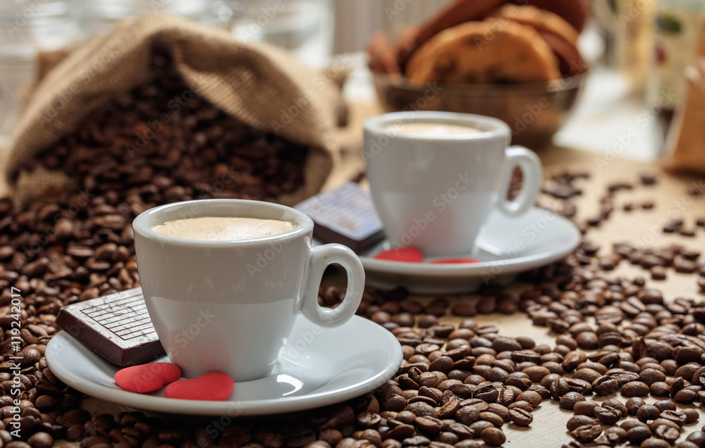 Coffee beans out of a sack and two cups of coffee Coffee beans out of a sack and two cups of coffee