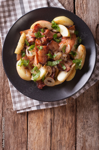 Swedish cuisine: Fried bacon with onion and stewed green apples close up. vertical top view 