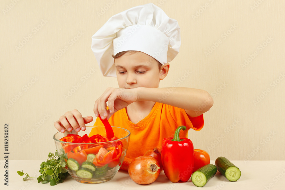 Young chef puts chopped vegetables for a salad in a bowl Young chef puts chopped vegetables for a salad in a bowl