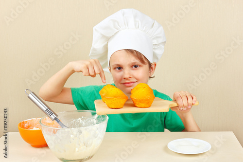 Young funny boy in chefs hat with a cooked the appetizing cake