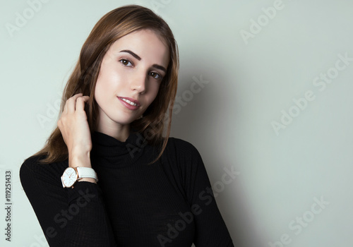 beautiful young woman with long hair posing in casual clothes and wearing a wrist watch
