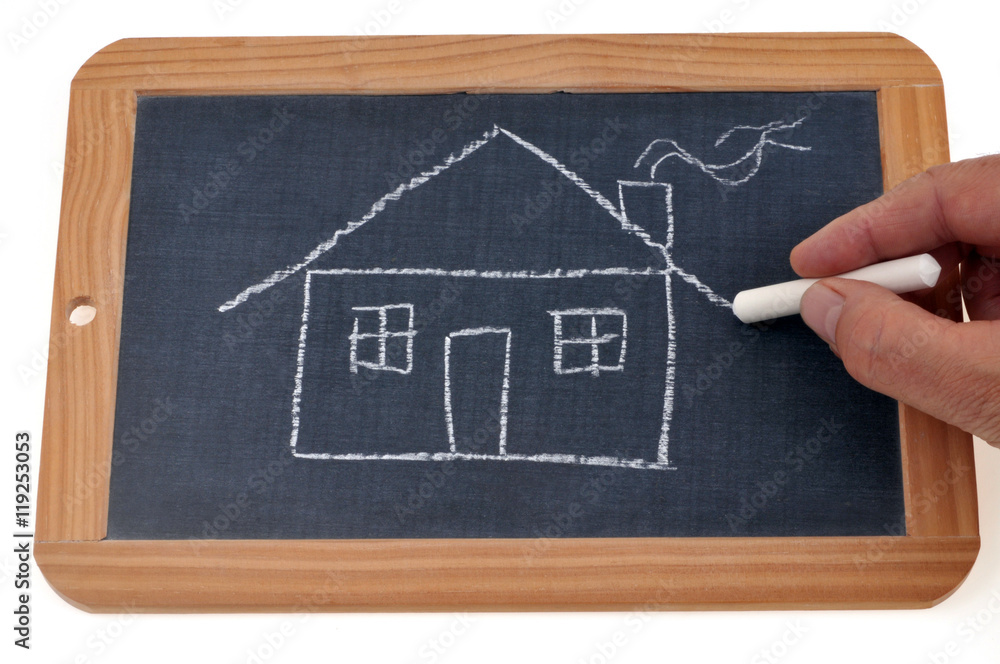 Personne dessinant une maison sur une ardoise Personne dessinant une maison sur une ardoise