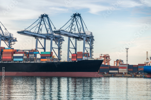 Container Cargo freight ship with working crane bridge in shipyard at dusk for Logistic Import Export background