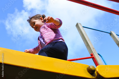 Little girl cross a playground bridge