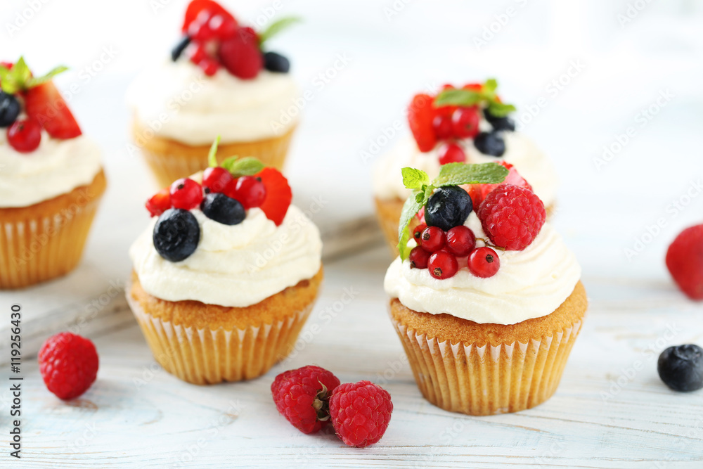 Tasty cupcakes with berries on white wooden table