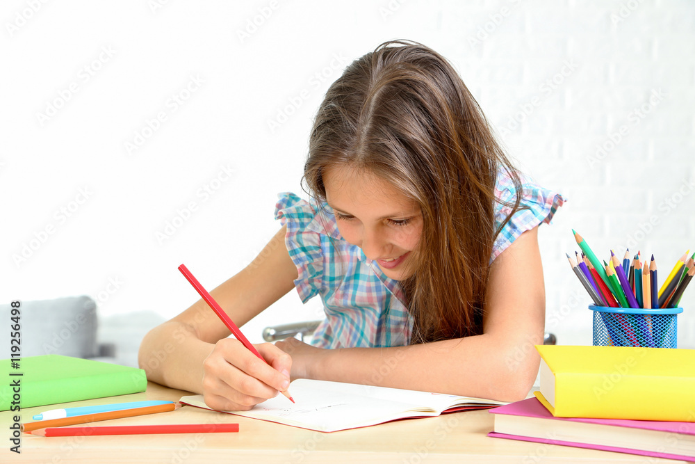 Young girl sitting at the desk and drawing Young girl sitting at the desk and drawing