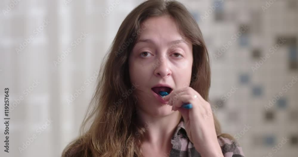 Attractive young woman without makeup brushes teeth while looking at her reflection in bathroom. Real time close up recorded at 24fps, front view from mirror POV. Attractive young woman without makeup brushes teeth while looking at her reflection in bathroom. Real time close up recorded at 24fps, front view from mirror POV.