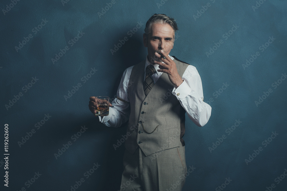 Retro businessman 1920s style smoking cigar and holding glass of Retro businessman 1920s style smoking cigar and holding glass of