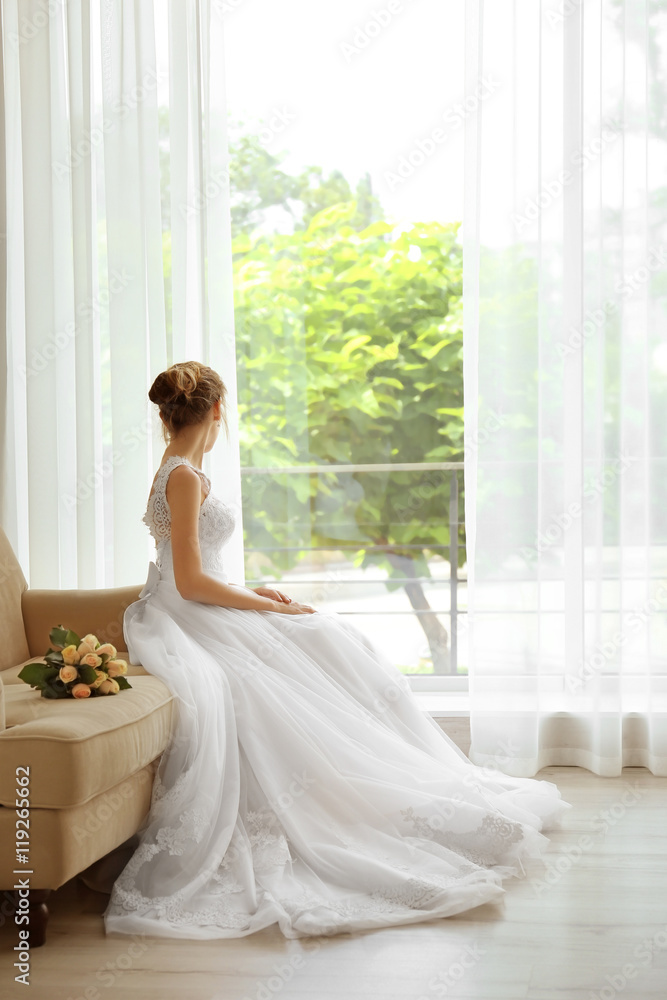 Bride in beautiful dress with wedding bouquet sitting on sofa Bride in beautiful dress with wedding bouquet sitting on sofa