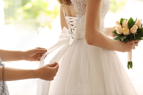 Bridesmaid tying bow on wed...