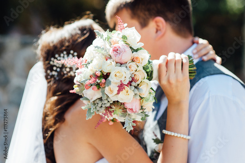 Photo bride and groom together holding wedding bouquet