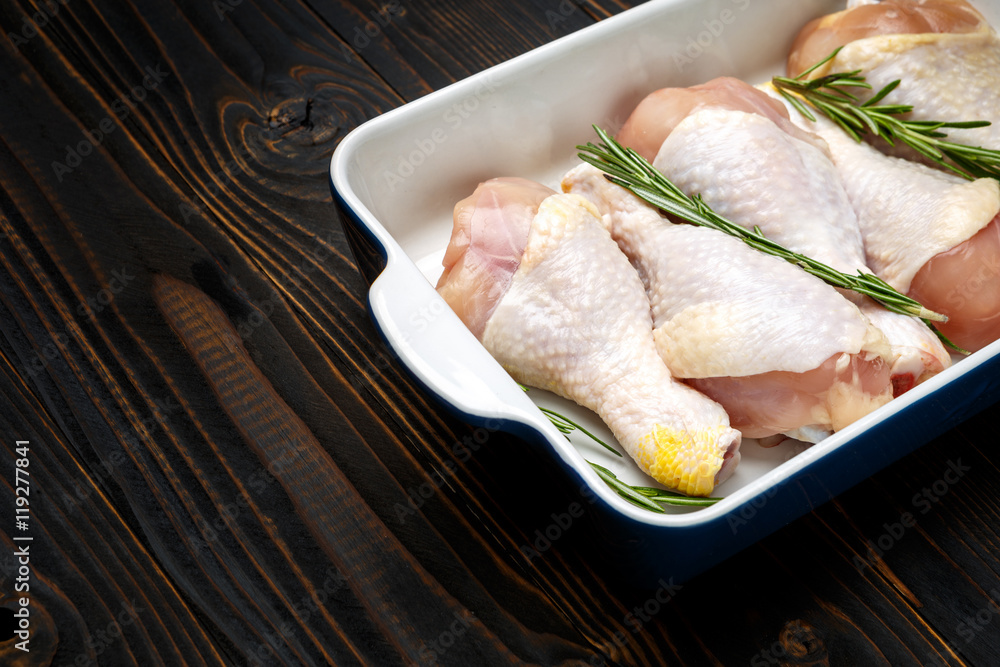 Raw chicken legs in baking dish on a wooden background Raw chicken legs in baking dish on a wooden background