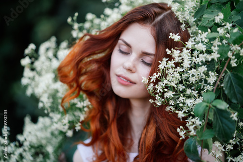 Fototapeta Naklejka Na Ścianę i Meble -  
beautiful young woman in a park on a background of flower
