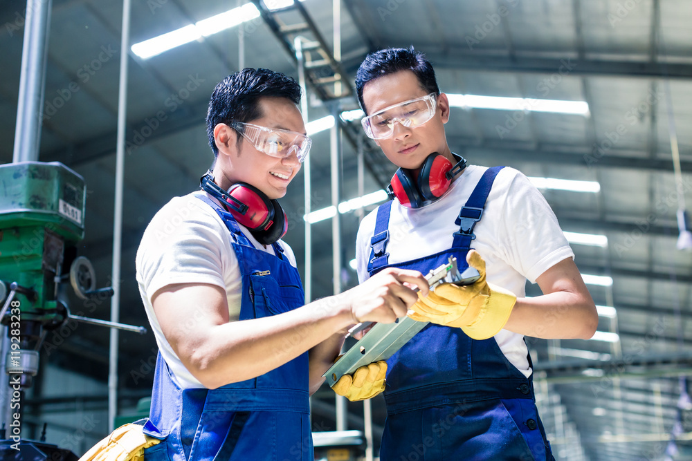 Two industrial workers inspecting work piece Two industrial workers inspecting work piece